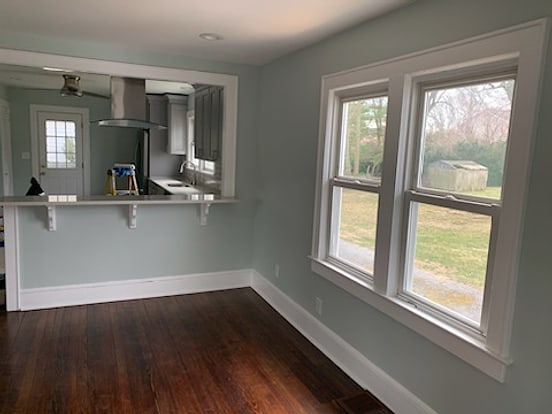 Living space painted soft sage with white trim and dark wood floors